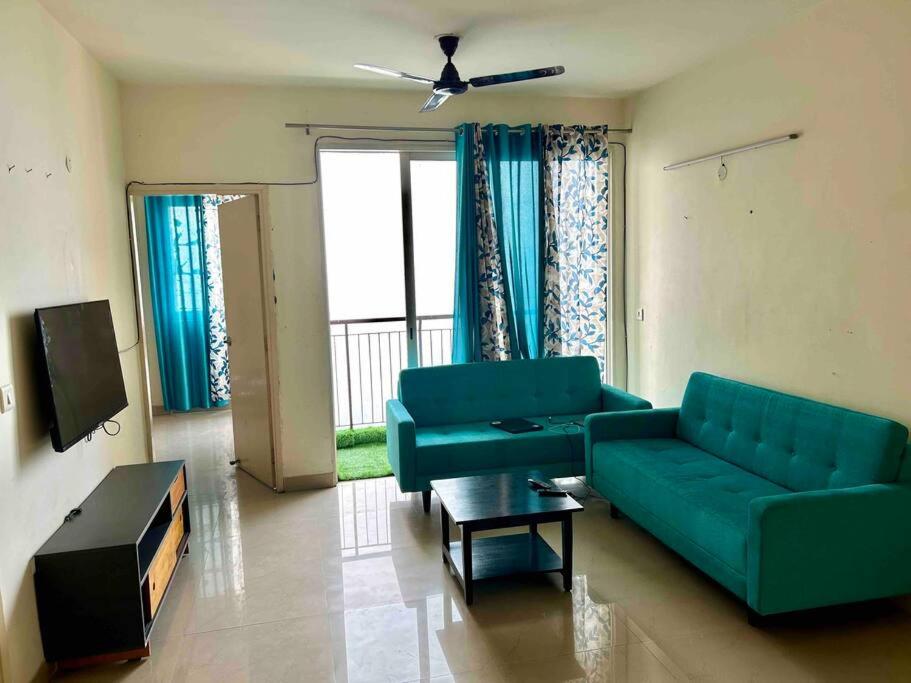 ein Wohnzimmer mit einem grünen Sofa und einem TV in der Unterkunft Friend's Place in Greater Noida
