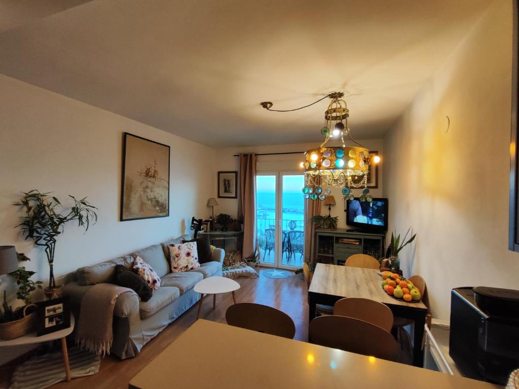 sala de estar con sofá y lámpara de araña en vista al mar Habitacion en apartamento compartido, en Moraira