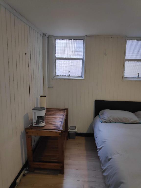 een slaapkamer met een bed, een tafel en 2 ramen bij Habitación privada tipo hotel, Baño, TV y WiFi. in Bogota