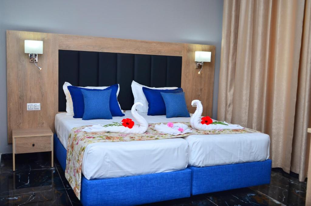Djerba的住宿－Hôtel Joya Paradise & SPA Djerba，两只天鹅坐在床上,床上有蓝色枕头