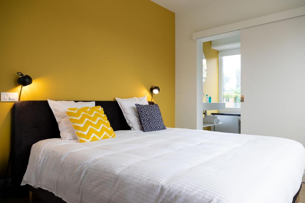 a bedroom with a large white bed with yellow walls at Tuss in Kortrijk