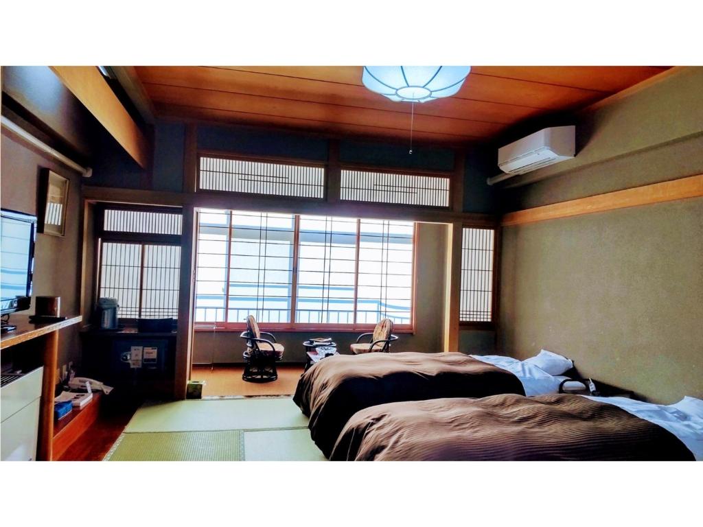 1 Schlafzimmer mit 2 Betten und einem großen Fenster in der Unterkunft Hotel Tenryukaku - Vacation STAY 16416v in Fukushima