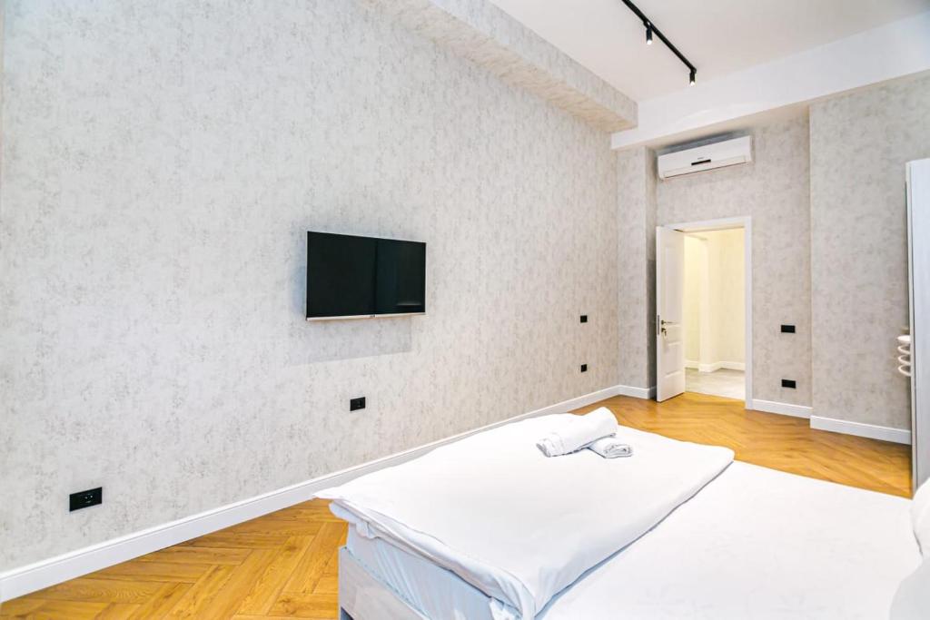 Habitación blanca con cama y TV en la pared en Two-Bedroom Apartment City Center en Baku