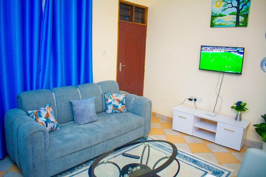 a living room with a blue couch and a tv at Unique Homes One- Bedroom Apartment in Kilifi