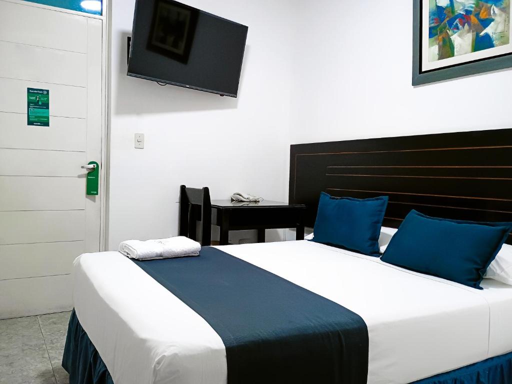 a bedroom with two beds and a tv on the wall at Di Costa Hotel in Piura