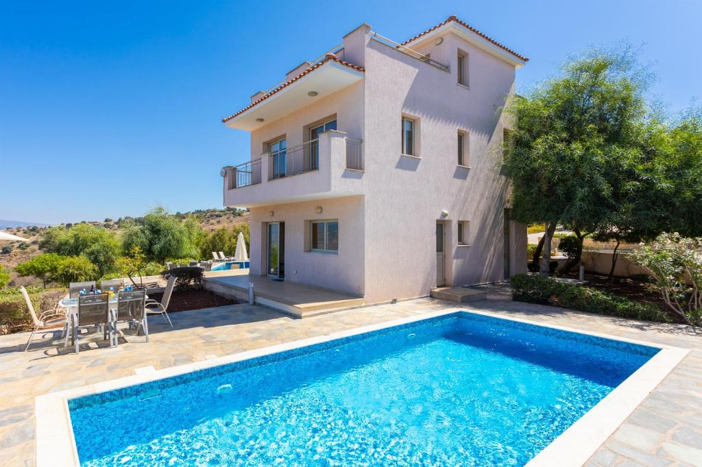 a villa with a swimming pool in front of a house at Villa Panorama Tessera in Droushia