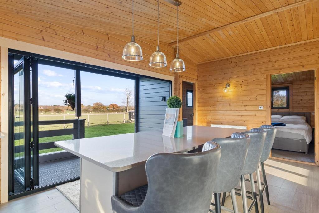 eine Küche mit einem Tisch und Stühlen sowie ein Schlafzimmer in der Unterkunft Choller Farm Lodge - Private Hot Tub in Slindon