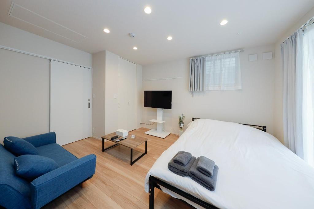 a bedroom with a bed and a blue couch and a tv at La Terrasse Higashikomagata - Vacation STAY 17380v in Tokyo