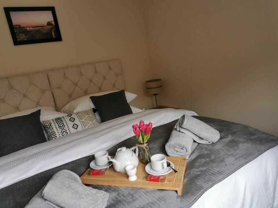 Una cama con una bandeja con set de té y flores. en The Woodpeckers - Alresford Essex, en Alresford