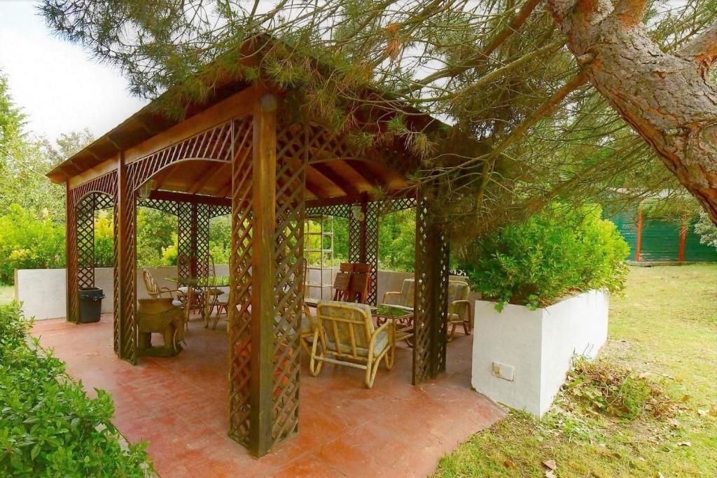 a wooden gazebo with tables and chairs under a tree at El Charrancito in El Espinar