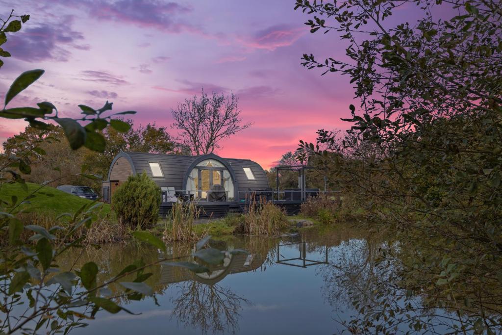 a house is reflected in a pond at sunset at Nestledstays- The Lake House in Arundel