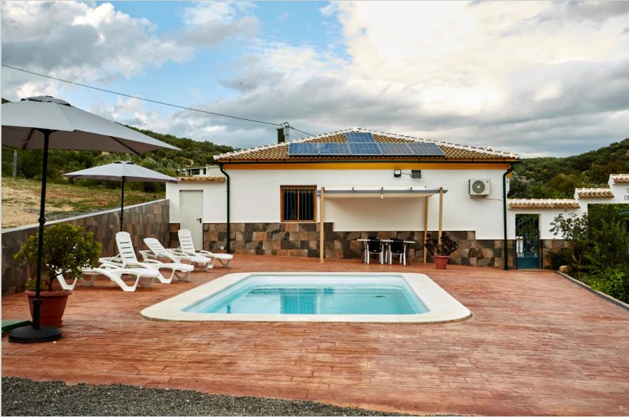 une maison avec une piscine, des chaises et un parasol dans l'établissement Casa Mártires, à Iznájar