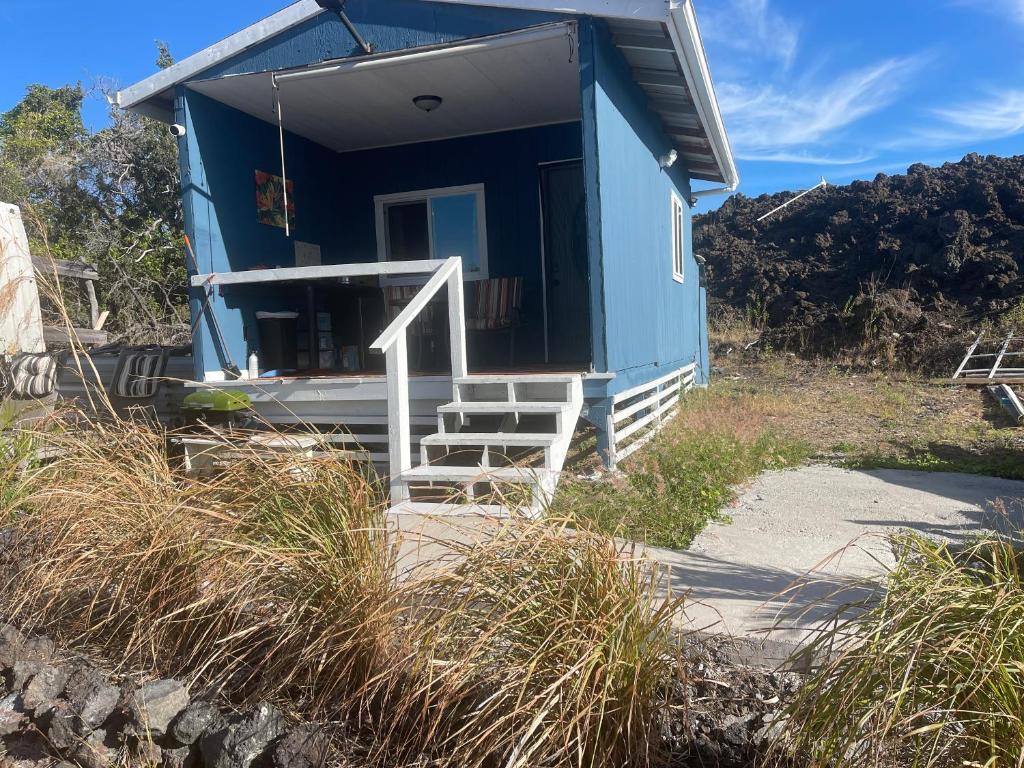 a blue tiny house on the side of a hill at The view in kau in Hawaiian Ocean View