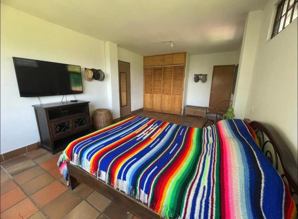 a bedroom with a colorful bed and a flat screen tv at Las Mañanitas Habitación Boreal in Medellín
