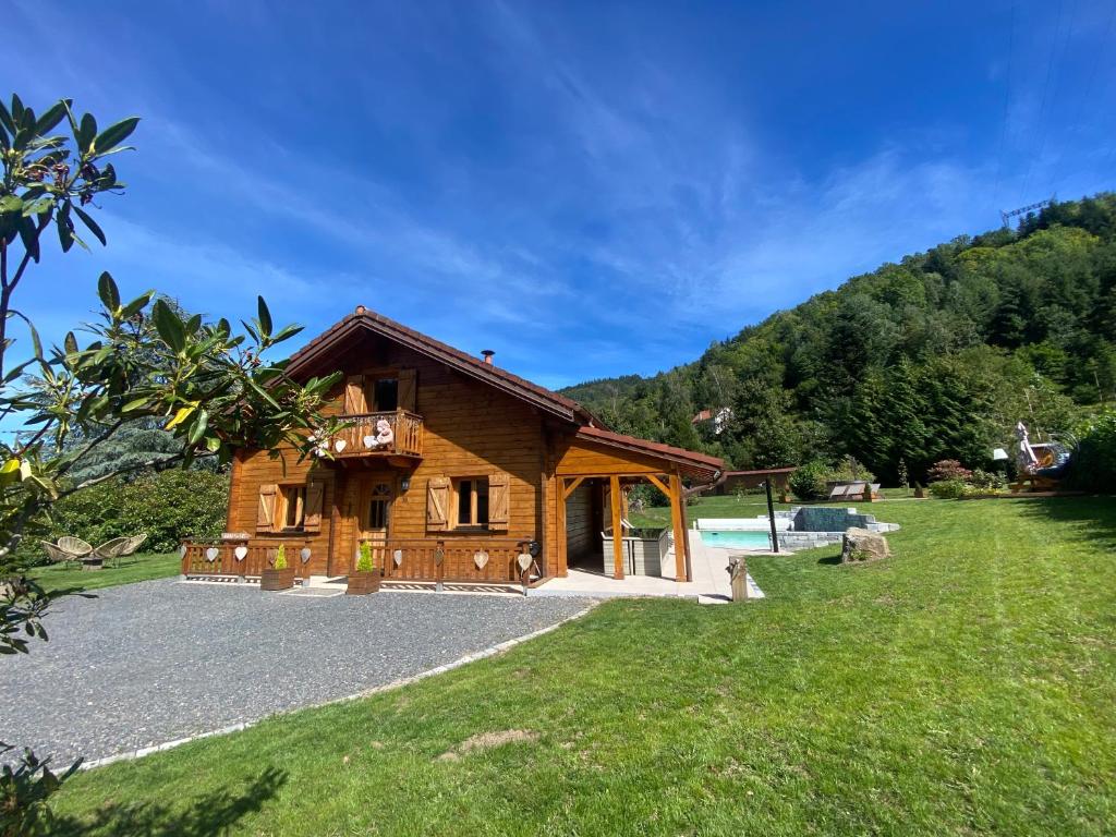 a log house with a swimming pool and a yard at Gîte Chalet avec bain nordique et piscine 11 pers Hautes Vosges in Plainfaing