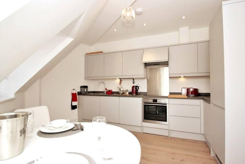 cocina con armarios blancos y mesa blanca en CC - Central Location Top Floor 2 Bed Deluxe Modern Apartment en Stratford-upon-Avon