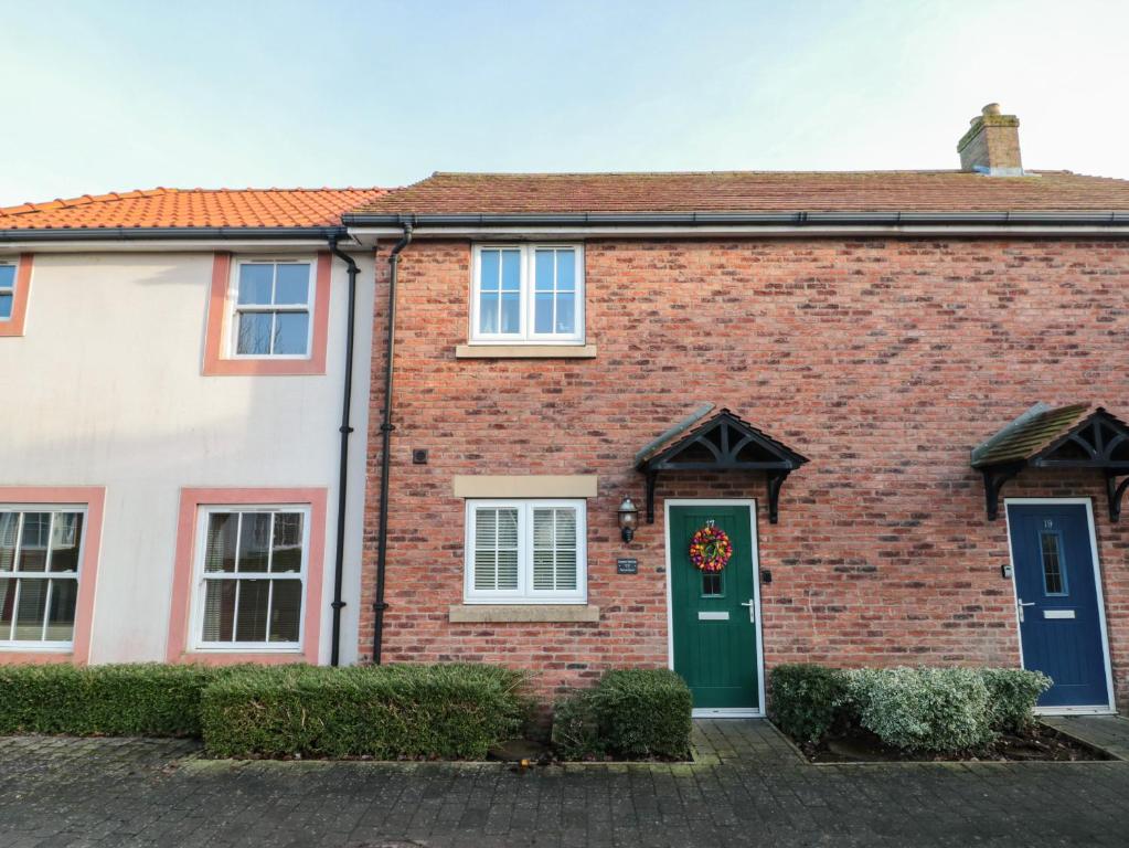 a red brick house with a green door at Coastal Retreat, The Bay in Filey
