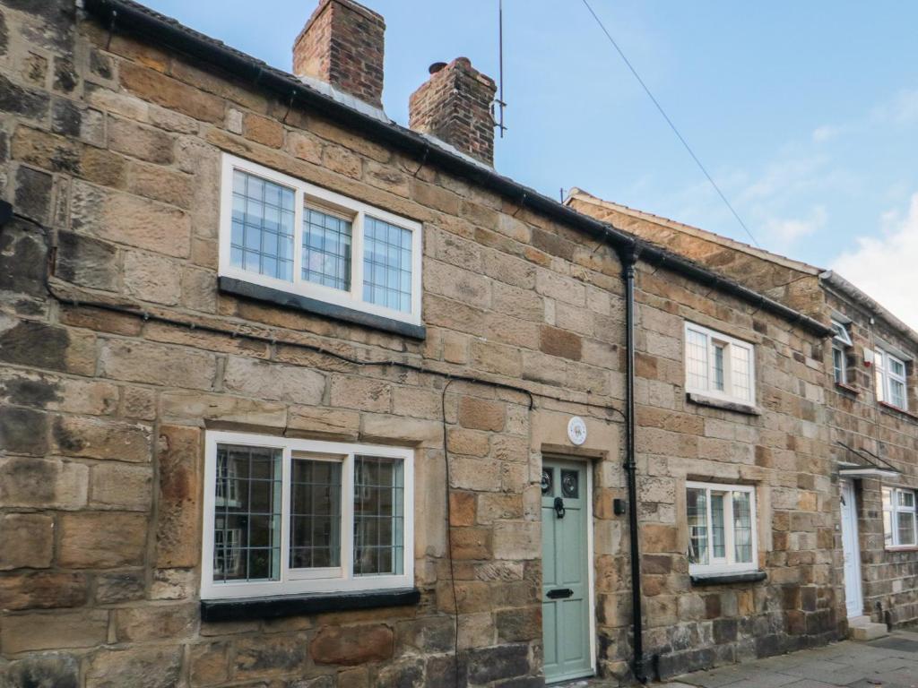 an old brick building with white windows and a door at Inglenook Cottage in Guisborough