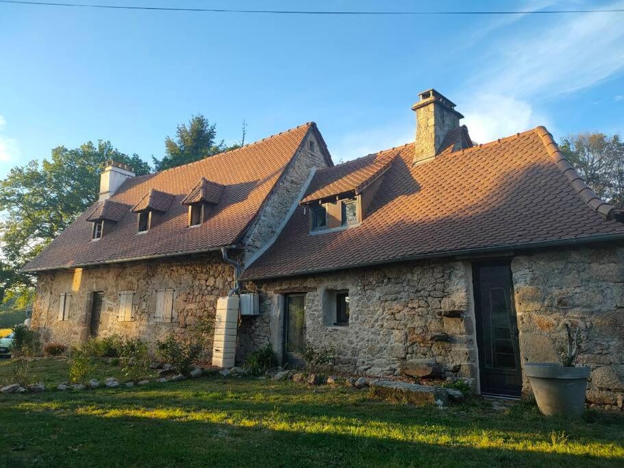 een oud stenen huis met een bruin dak bij La maisonette de Raphaël in Saint-Mamet-la-Salvetat
