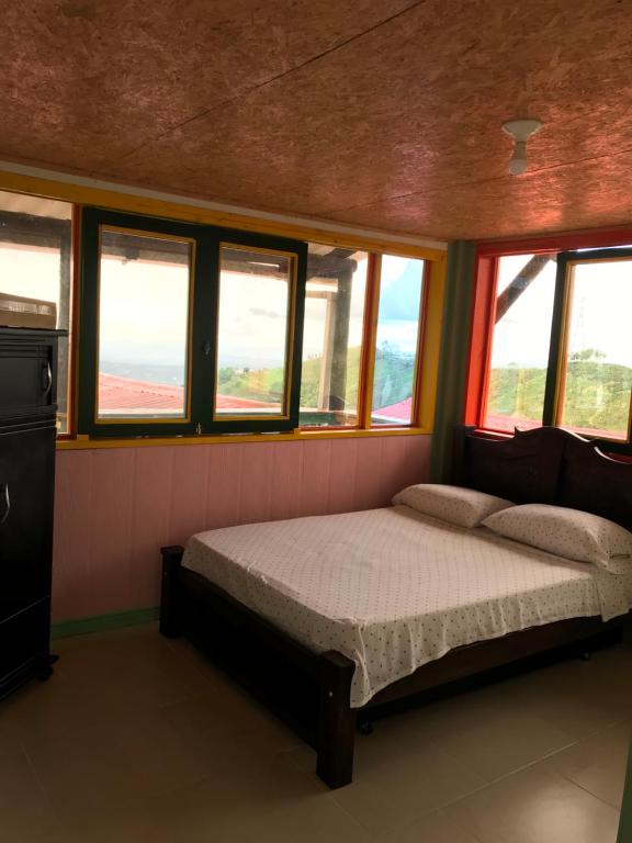1 dormitorio con 1 cama en una habitación con ventanas en Reserva Natural Finca La Cabaña, en Dosquebradas