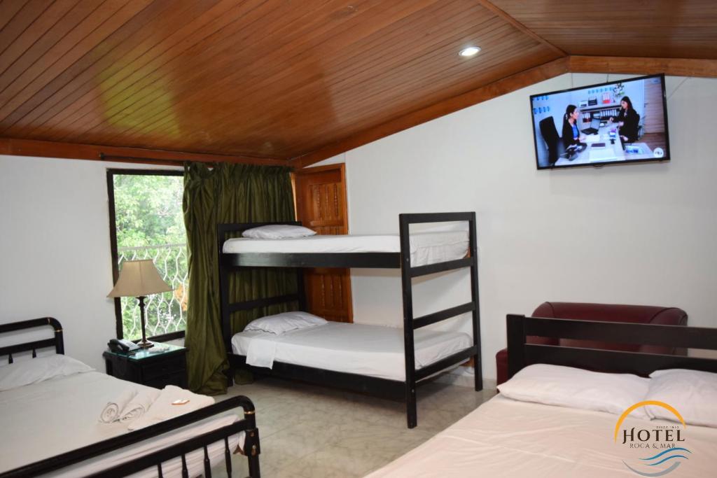 a bedroom with two bunk beds and a flat screen tv at Hotel Roca & Mar in Santa Marta