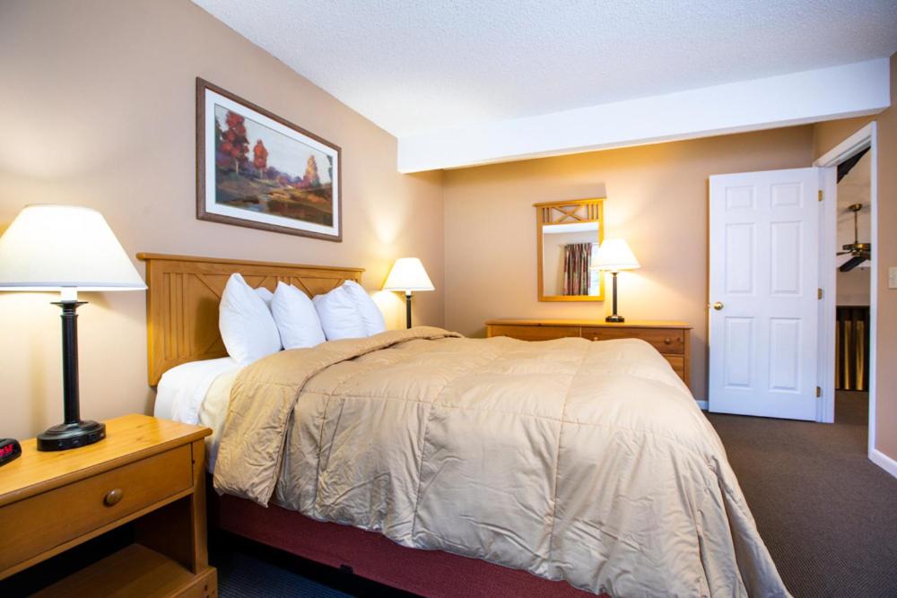 a hotel room with a large bed with two lamps at Lake Placid Club Lodges in Lake Placid