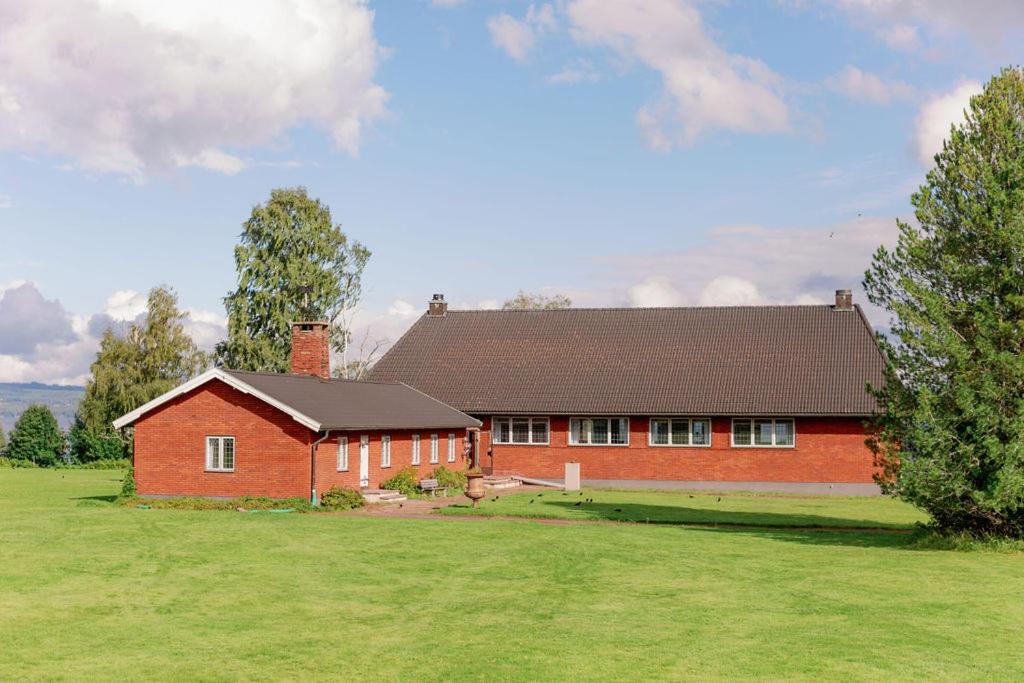 a red house in a field with a large yard at Bonäs bygdegård in Mora
