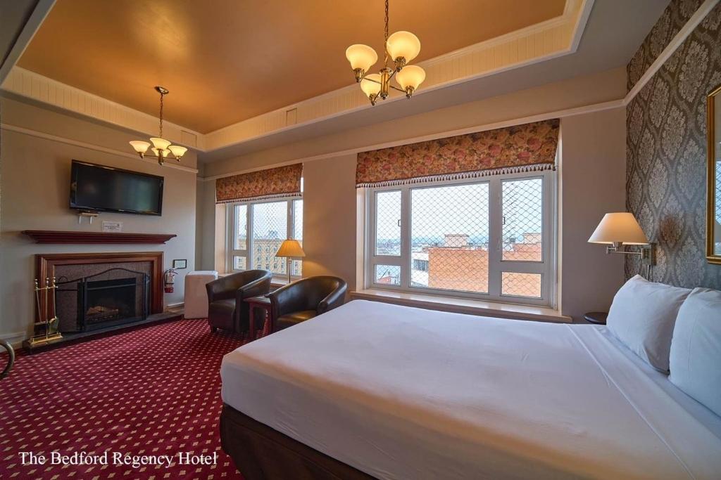 a hotel room with a large bed and a fireplace at The Bedford Regency Hotel in Victoria