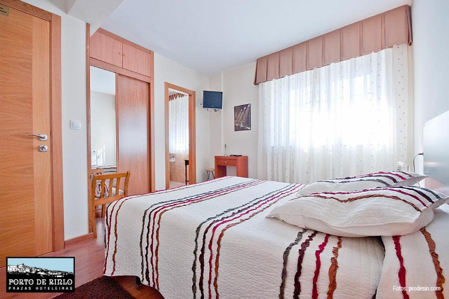 Porto de Rinlo في رينلو: غرفة نوم بسرير وبطانية مخططة