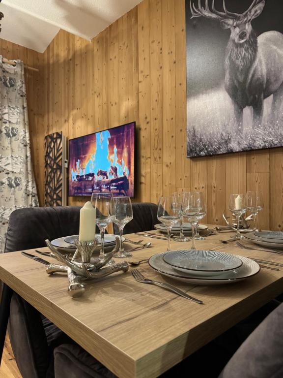 a wooden table with glasses and a deer on the wall at Cocon au cœur de Chamonix avec parking gratuit in Chamonix-Mont-Blanc