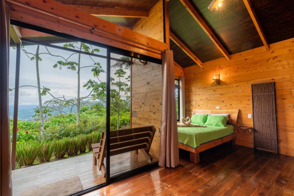 a bedroom with a green bed and a large window at Cabaña El Ciprés: Vistas increíbles y Mirador in Turrialba
