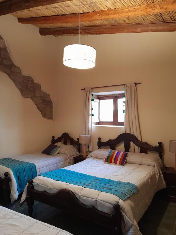 a bedroom with two beds and a window at La Casa del Indio in Tilcara