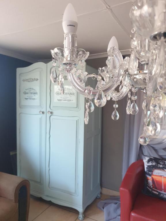 einen Kronleuchter im Wohnzimmer mit einem roten Stuhl in der Unterkunft VillaMed Guesthouse in Klerksdorp