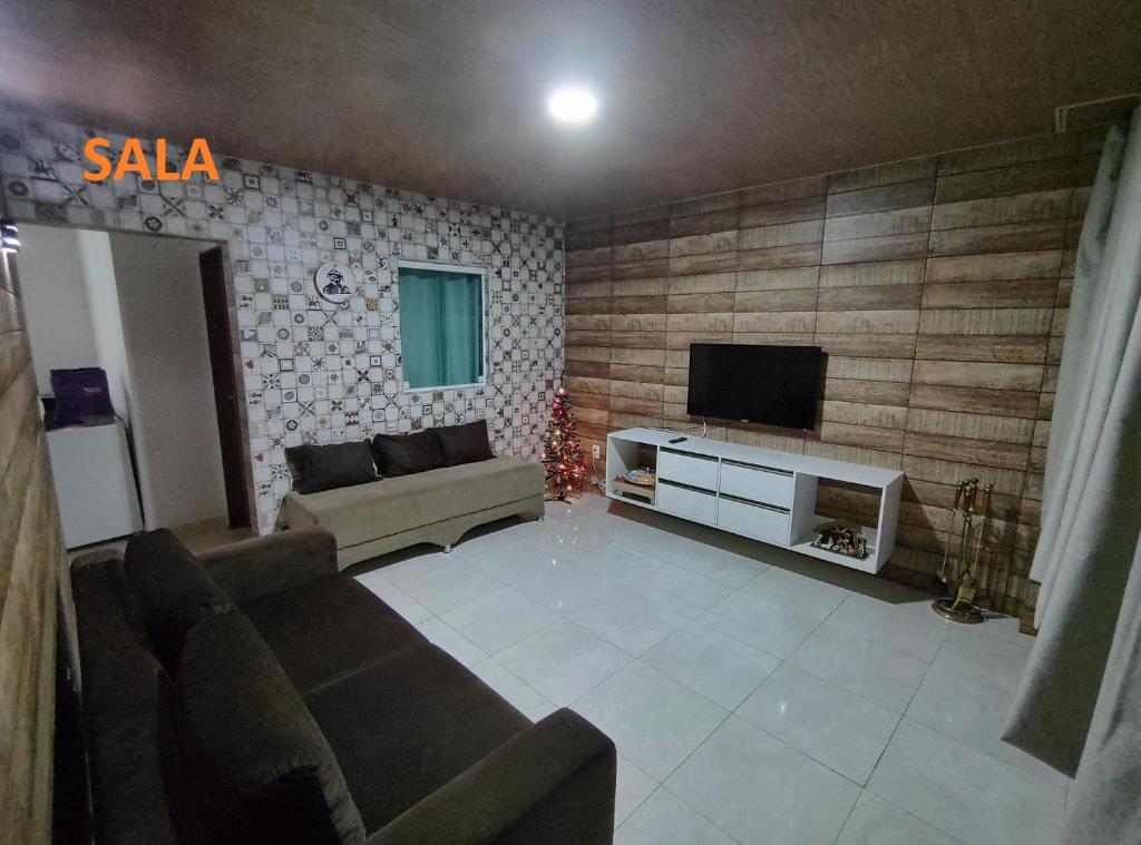 ein Wohnzimmer mit einem Sofa und einem TV in der Unterkunft Apartamento com três suítes em Garanhuns próximo ao Parque Euclides Dourado in Garanhuns