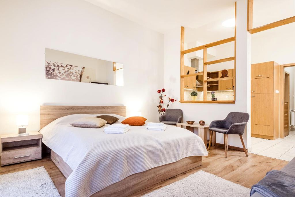 Un dormitorio blanco con una cama grande y una silla. en Downtown charm with balcony and garden view, en Budapest