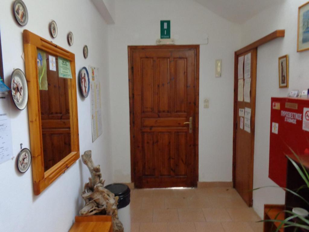 a hallway with a wooden door and plates on the wall at Savas Rooms in Palaiochóra