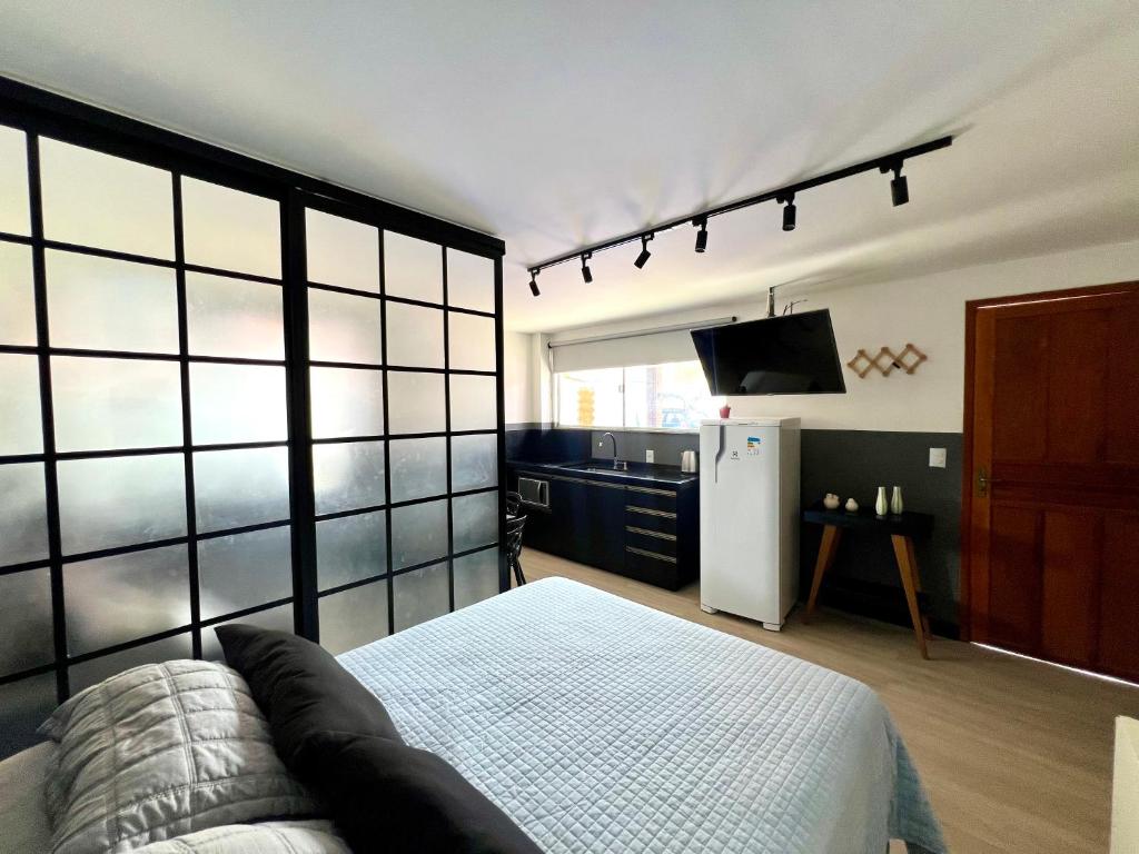 a room with a bed and a refrigerator and a tv at Pousada Ilha do Campeche in Florianópolis
