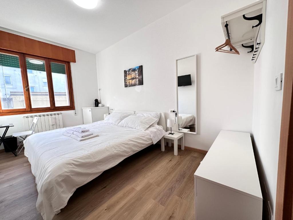 una camera bianca con un grande letto e uno specchio di Calima apartments a Marghera