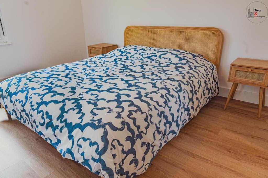 a bed with a blue and white blanket on it at Le reflet chic - 2 pièces neuf - quartier calme à 5 min de Strasbourg in Schiltigheim
