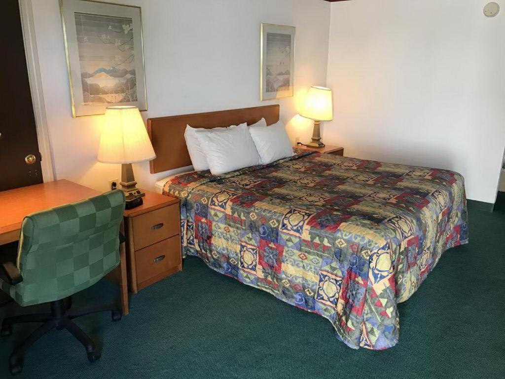 a hotel room with a bed and a desk and two lamps at Loyalty Inn Maryville in Maryville