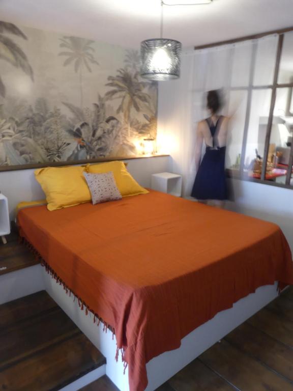 a bedroom with a large orange bed with a woman in the background at Studio Poe Rava in Papeete