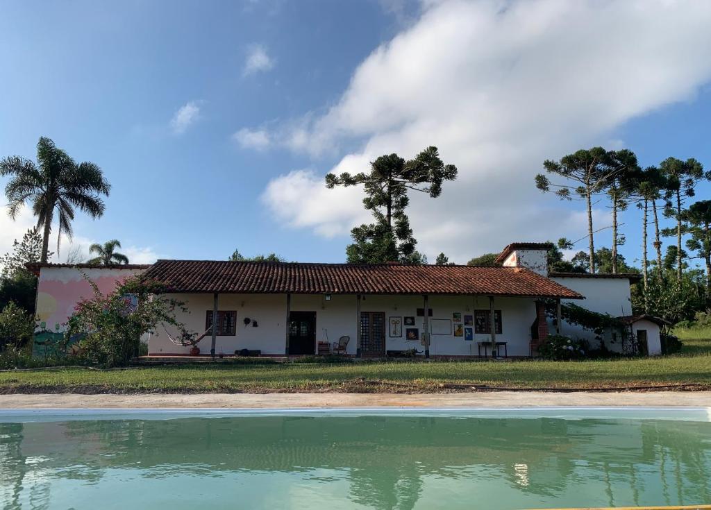 une maison avec une piscine d'eau en face de celle-ci dans l'établissement Casa de Fazenda na Ecovila Sustentar, 38km de SP, à Embu-Guaçu