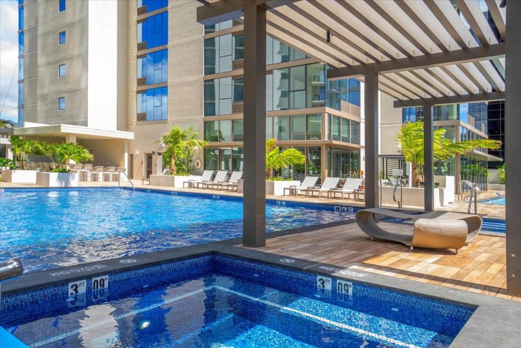 a swimming pool at a hotel with a building in the background at Sky Ala Moana 2307 condo in Honolulu