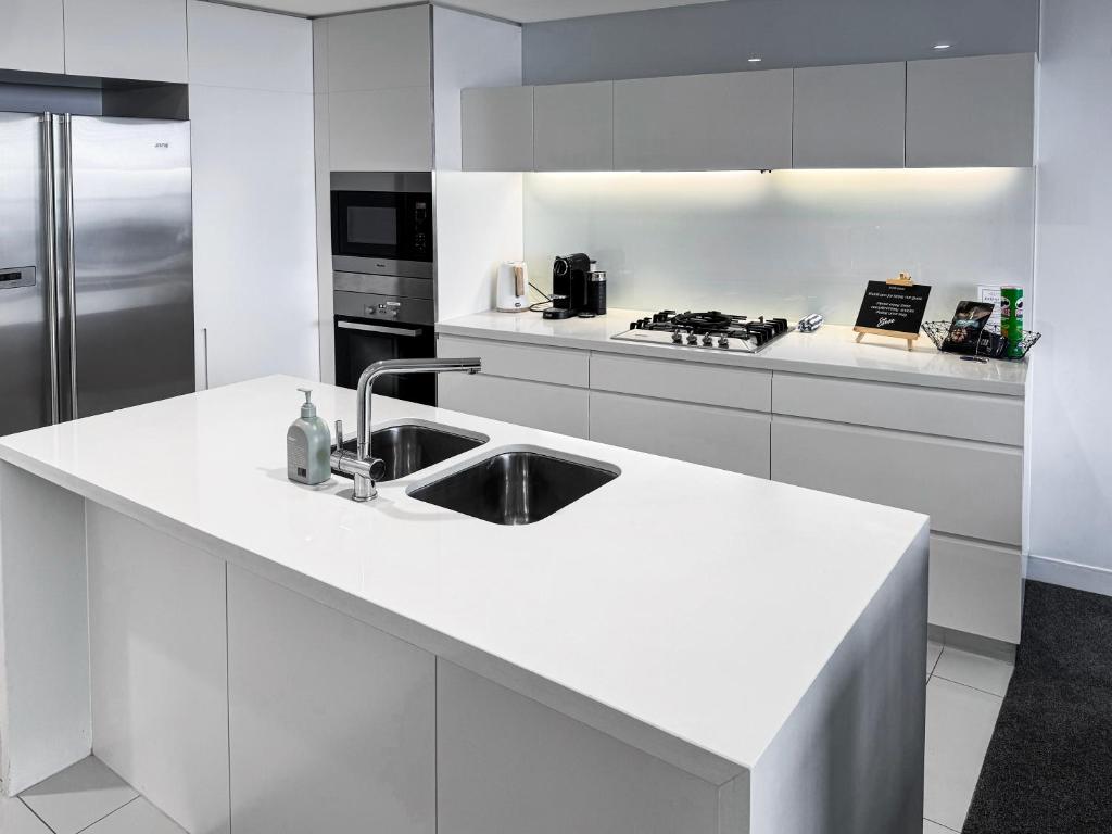 a white kitchen with a sink and a refrigerator at Oracle 11th floor Tower 1 - GC Getaways in Gold Coast