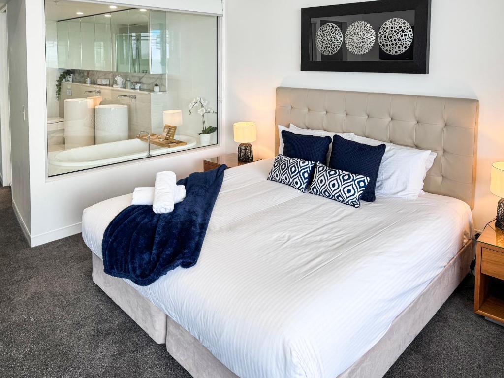 a bedroom with a large white bed with blue pillows at Oracle 11th floor Tower 1 - GC Getaways in Gold Coast