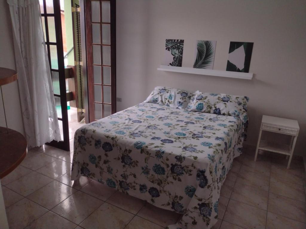 a bedroom with a bed with a flowered bedspread at Casa Caraguá in Caraguatatuba