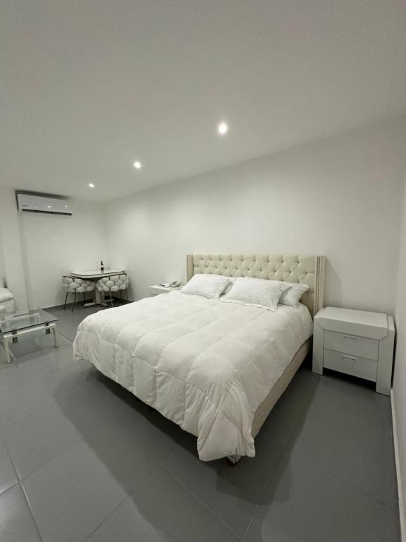 a white bedroom with a large bed and a table at Cantares Adults Only in Cancún