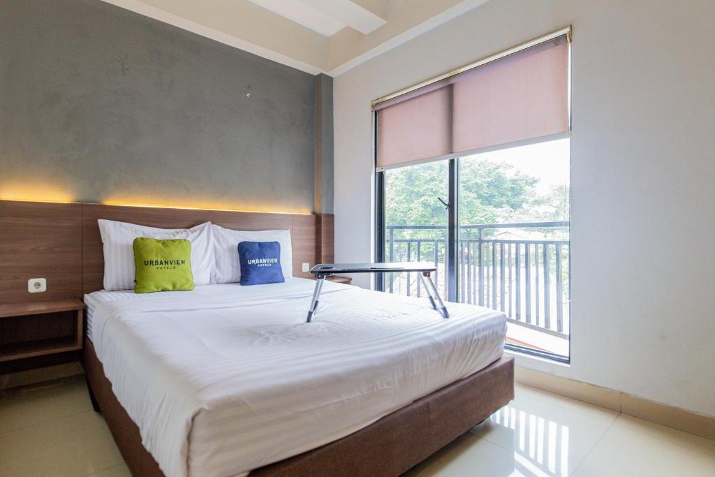 a bedroom with a bed and a large window at Urbanview Hotel Slipi Inn Palmerah in Jakarta