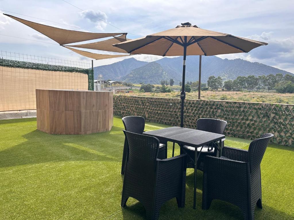 a table and chairs with an umbrella on a lawn at Los toronjos in Tequila
