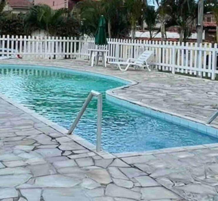 ein Pool neben einem weißen Zaun in der Unterkunft Casa Em condomínio portaria24 horas,piscina in Cabo Frio